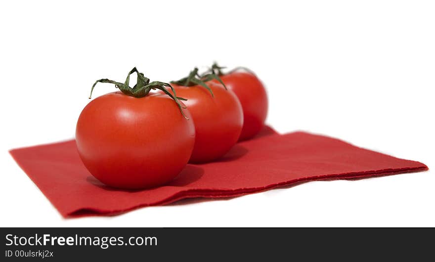 A row of red tomatoes lying on the red napkin.