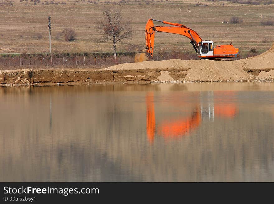 Orange digger at the lake coast