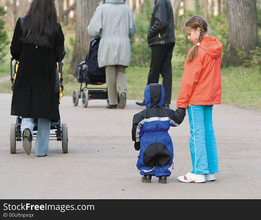 The girl-teenager with the younger brother cost and look at passing by people. The girl-teenager with the younger brother cost and look at passing by people