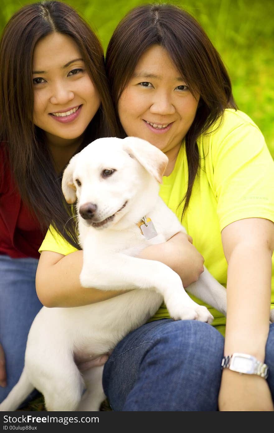 Two beautiful asian women holding a labrador dog in a park. Two beautiful asian women holding a labrador dog in a park