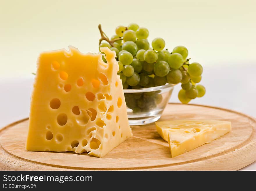 Piece of cheese on the board and grapes