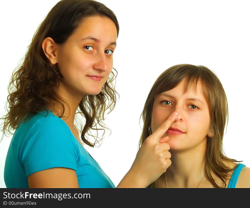 A pretty lady with brown hair puts on her forefinger to an other blond girl's nose. A pretty lady with brown hair puts on her forefinger to an other blond girl's nose