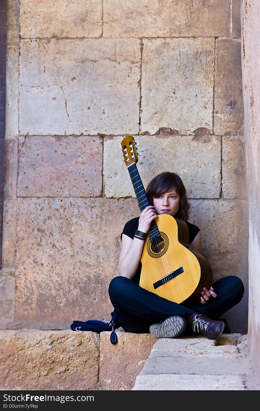 Young guitar performer against brickwall