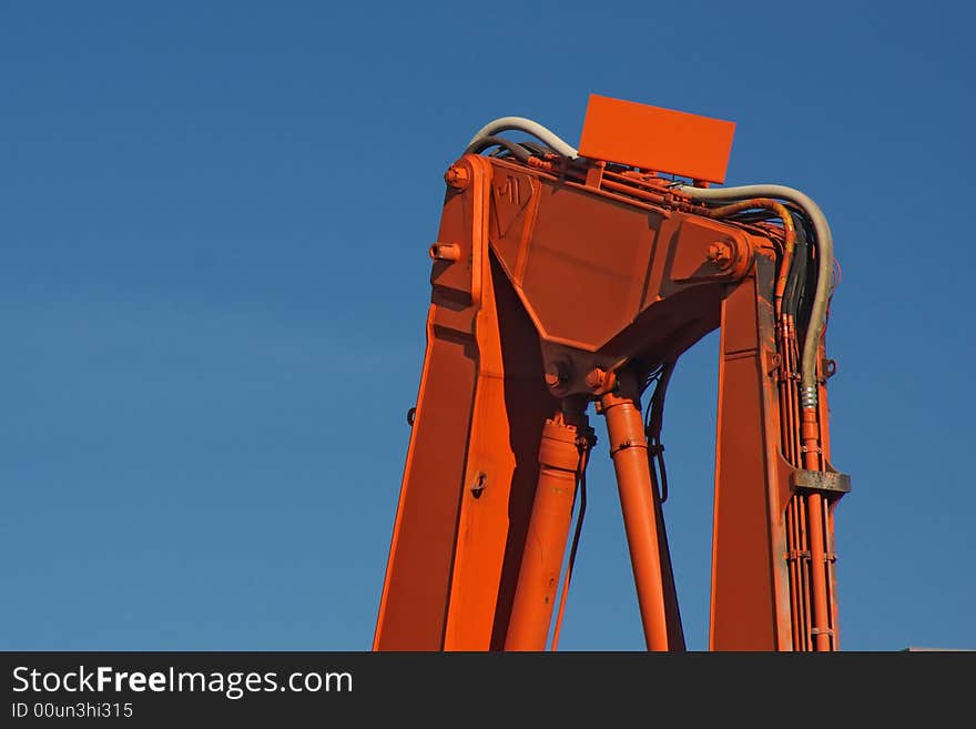 Orange backhoe construction equipment against blue sky. Orange backhoe construction equipment against blue sky