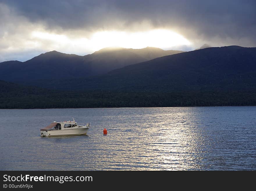 A boat moored in New Zealand floating on the reflecting waters. A boat moored in New Zealand floating on the reflecting waters.