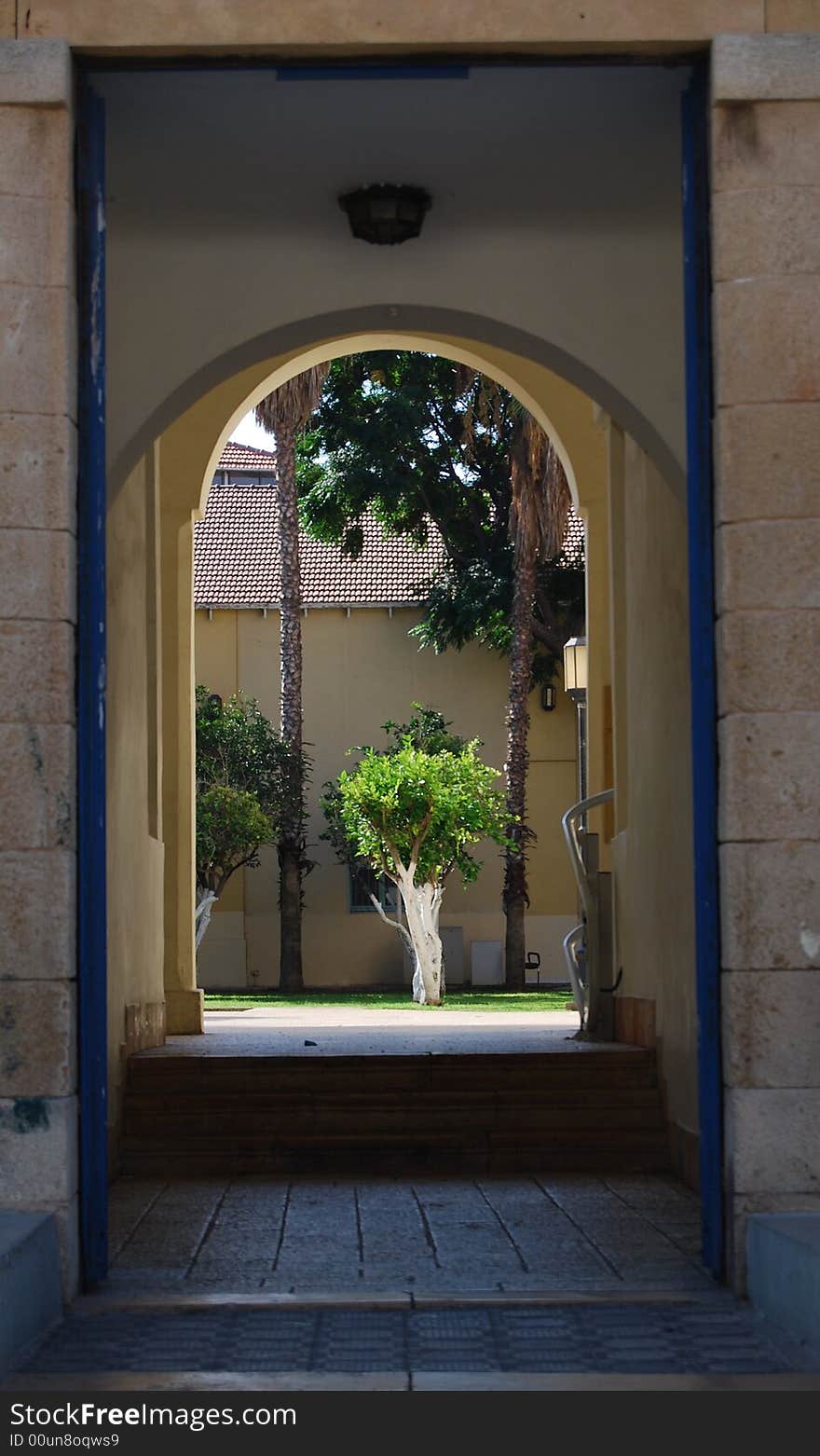 Entrance in the arch of building and in center green tree