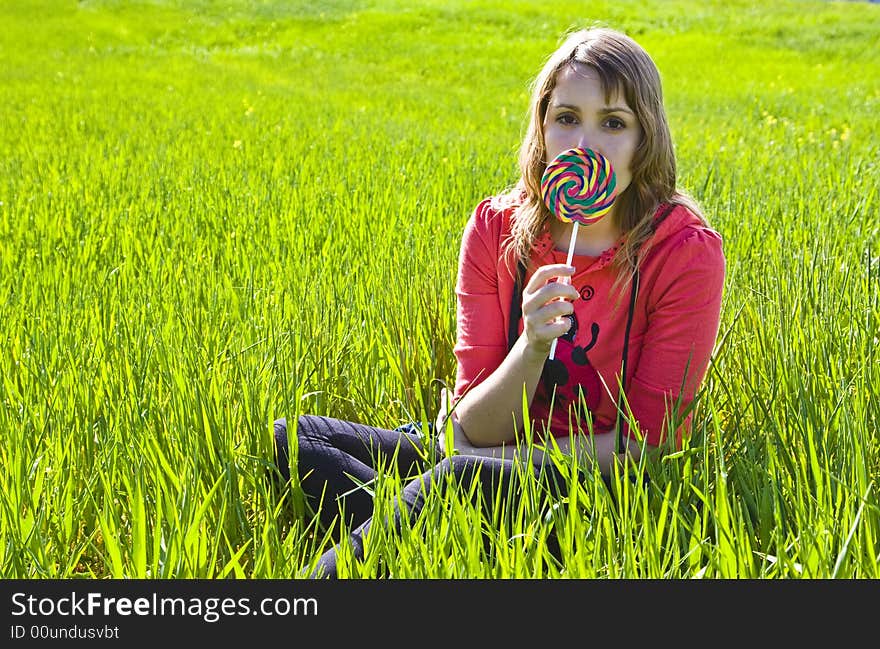 Blonde cutie behind spiral candy on green background. Blonde cutie behind spiral candy on green background