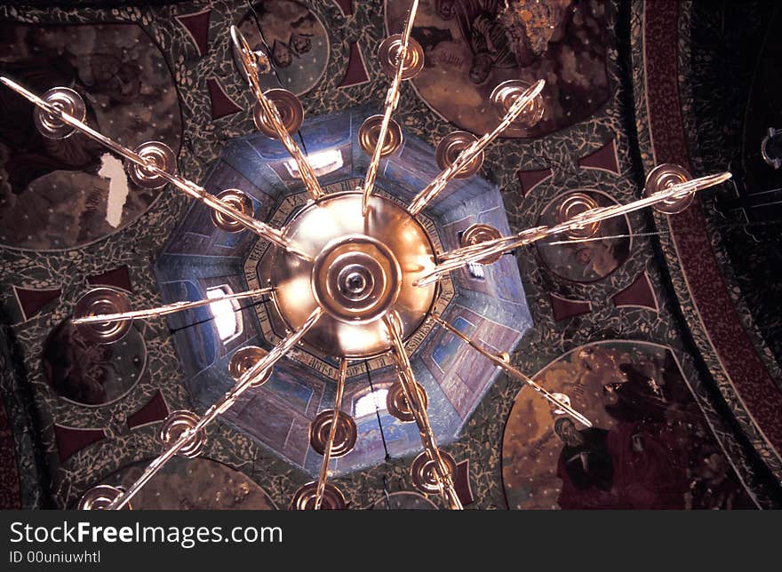 A view from below a golden chandelier in a church.