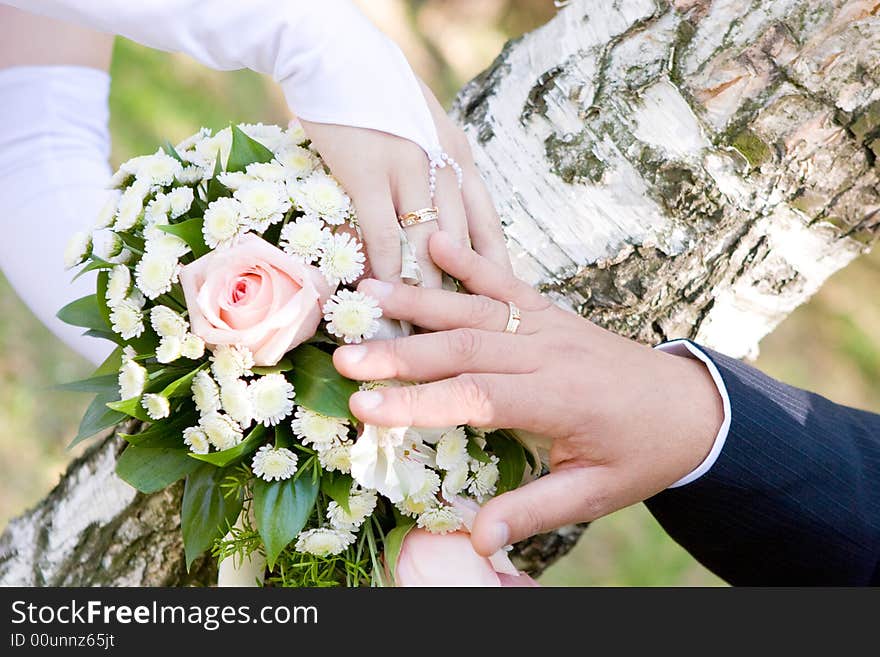 Two hands of bride and groom over a wedding bouquet. Two hands of bride and groom over a wedding bouquet