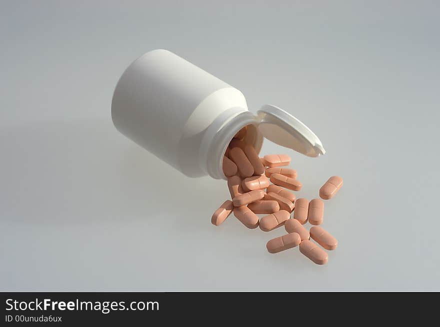 Medicine pills with a white bottle on a grey background. Close-up