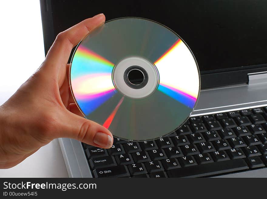 Close up. Woman with cd disk in a hand used notebook. White background