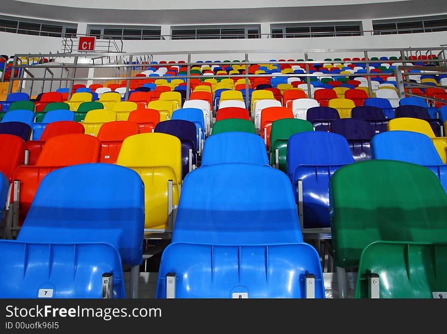 Several rows of multi-coloured plastic stadium seats