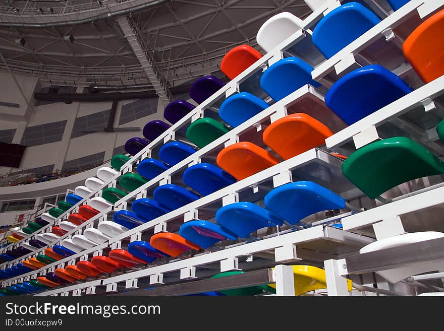 Several rows of multi-coloured plastic stadium seats