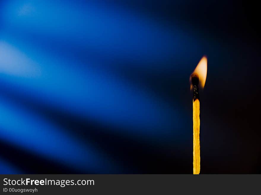 Flame of matchstick against blue background