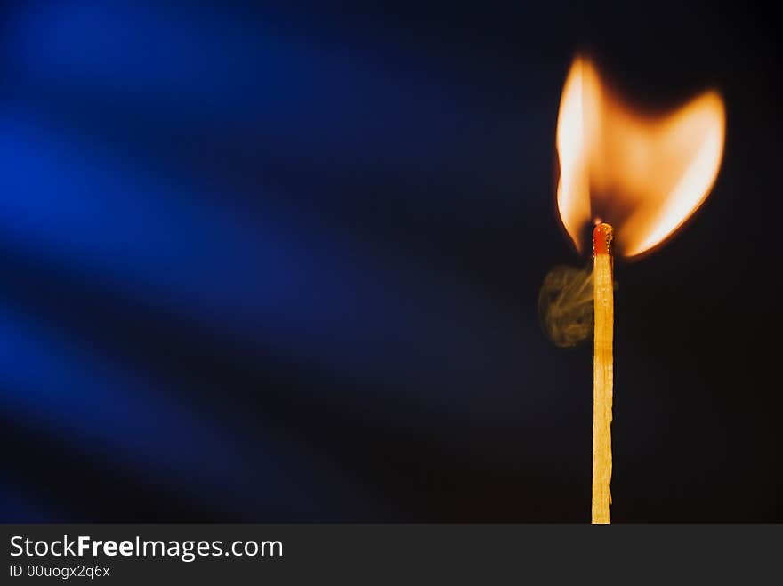 Flame of matchstick against blue background