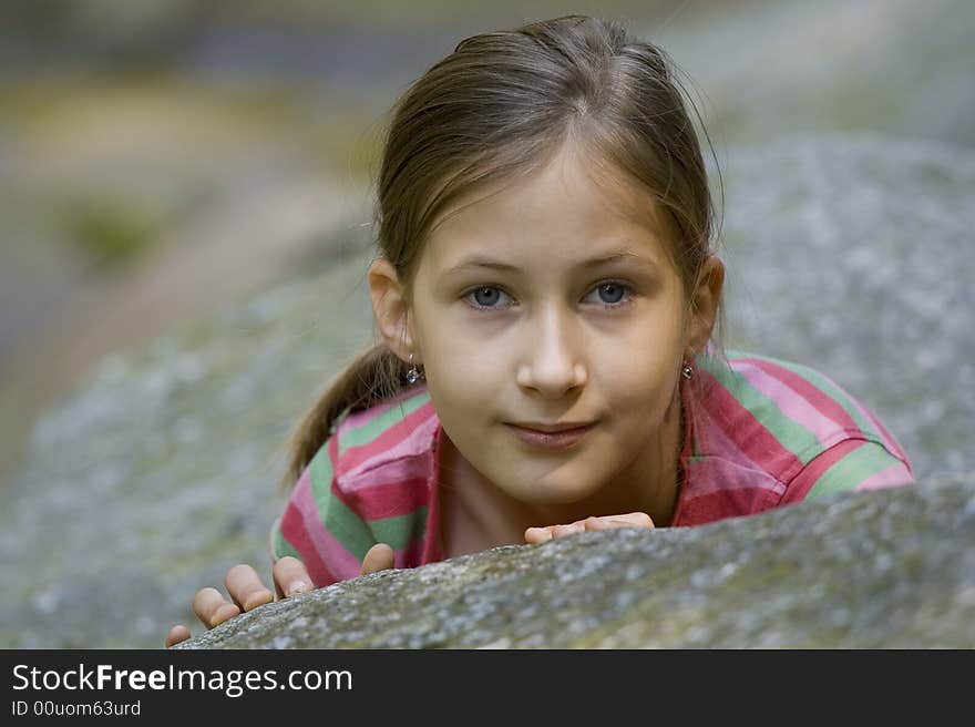 Girl looking from behind the stone