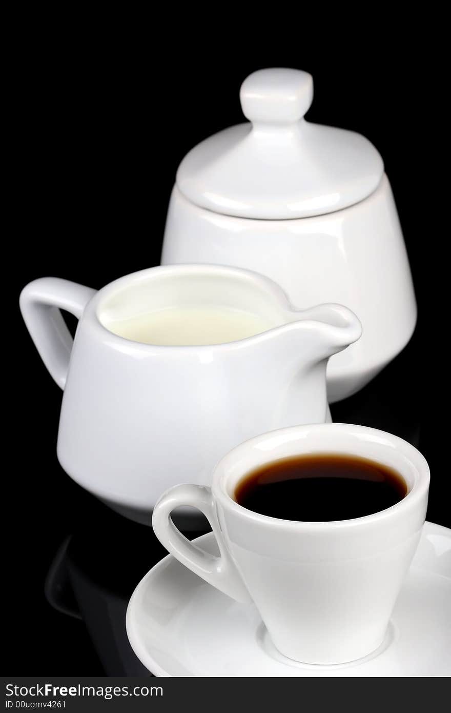 Cup of coffee, sugar and milk pot over black background