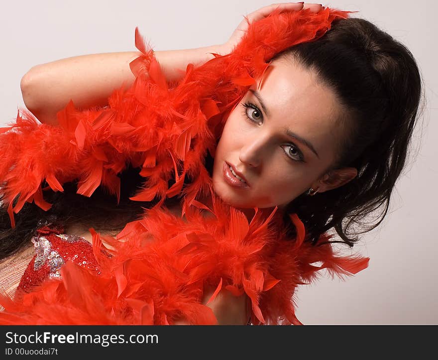 The beautiful girl in a red boa on grey background