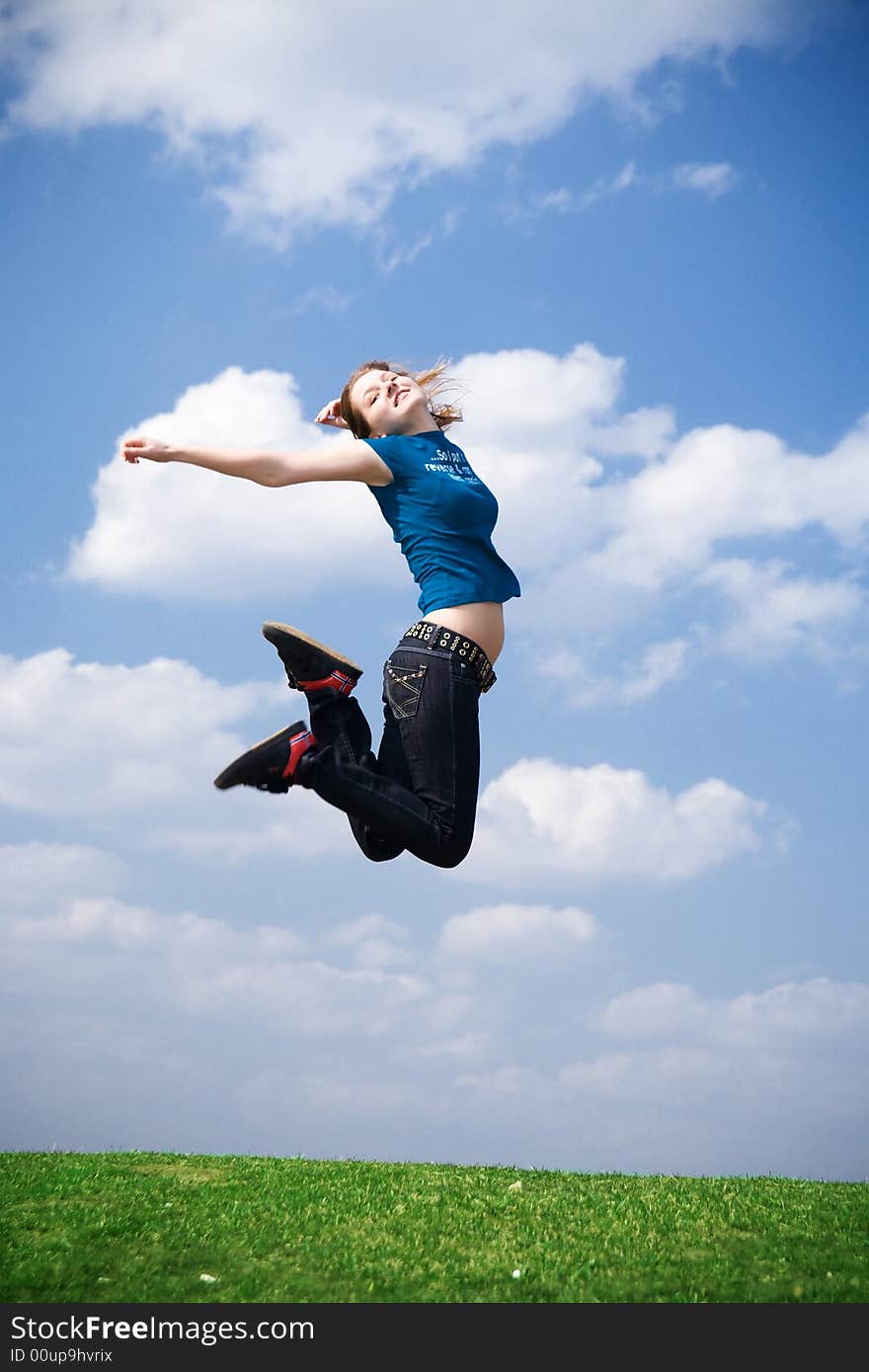 The happy jumping girl on a background of the blue sky