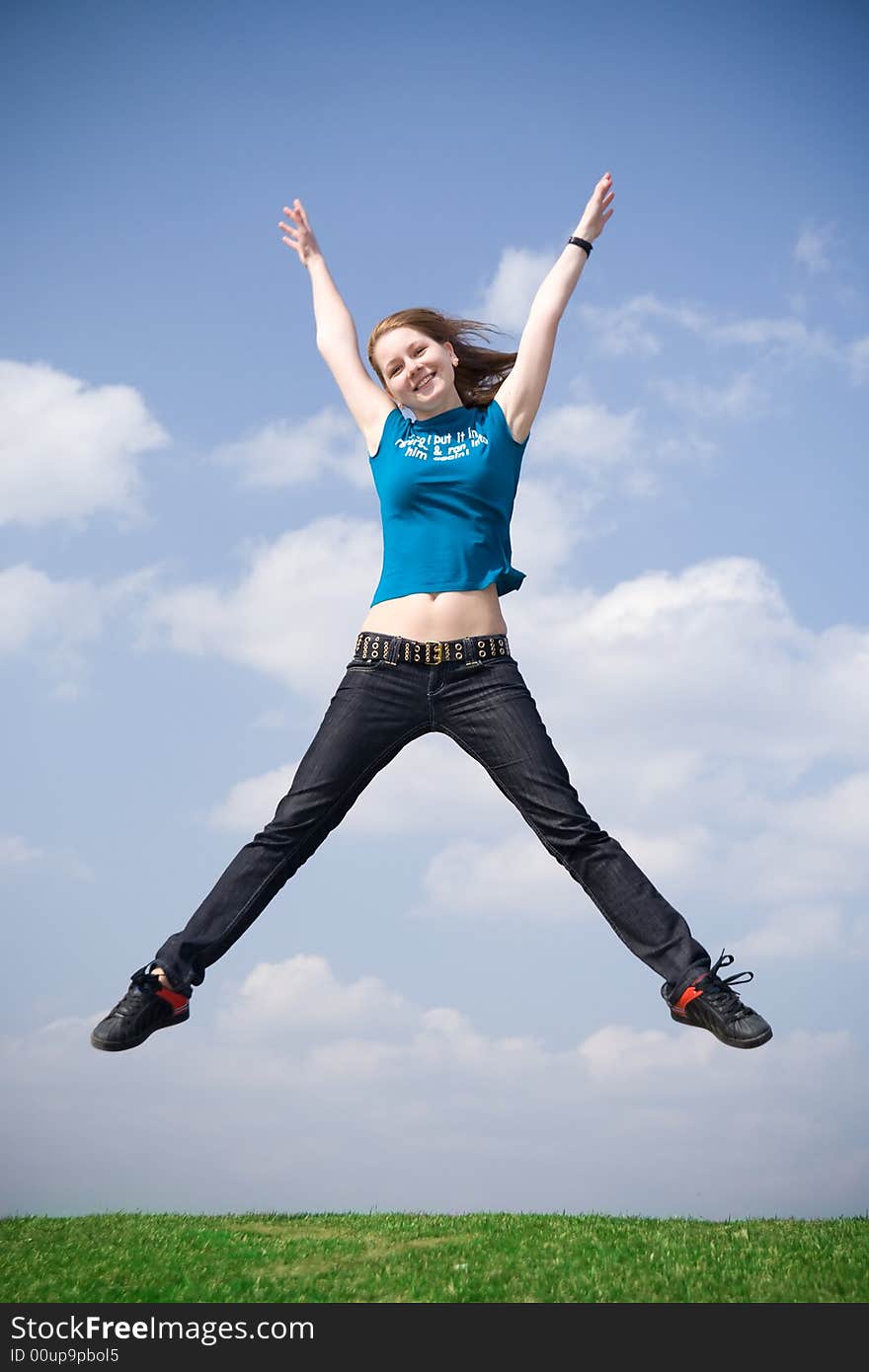 The happy jumping girl on a background of the blue sky