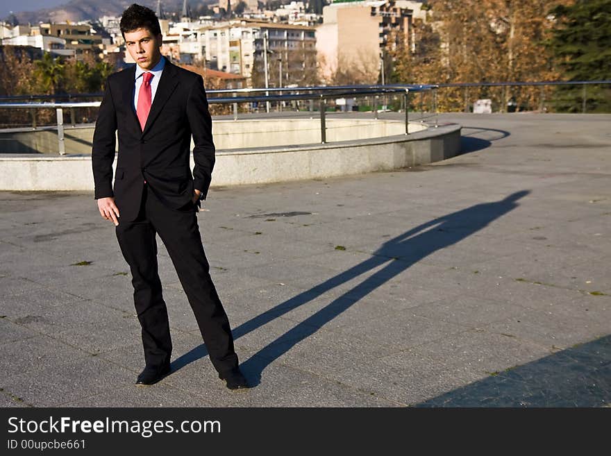 Standing businessman posing on city background