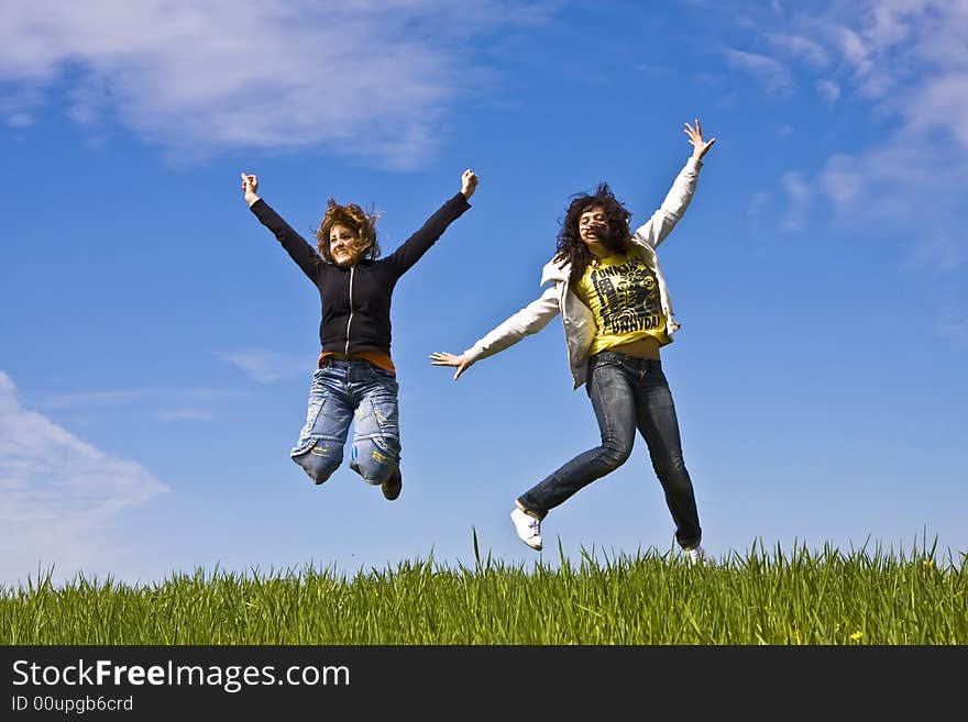 Young friends jumping on green meadow