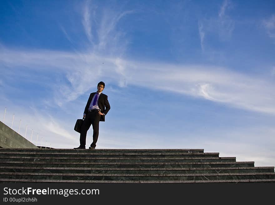 Businessman posing on stairs against blue sky. Businessman posing on stairs against blue sky.