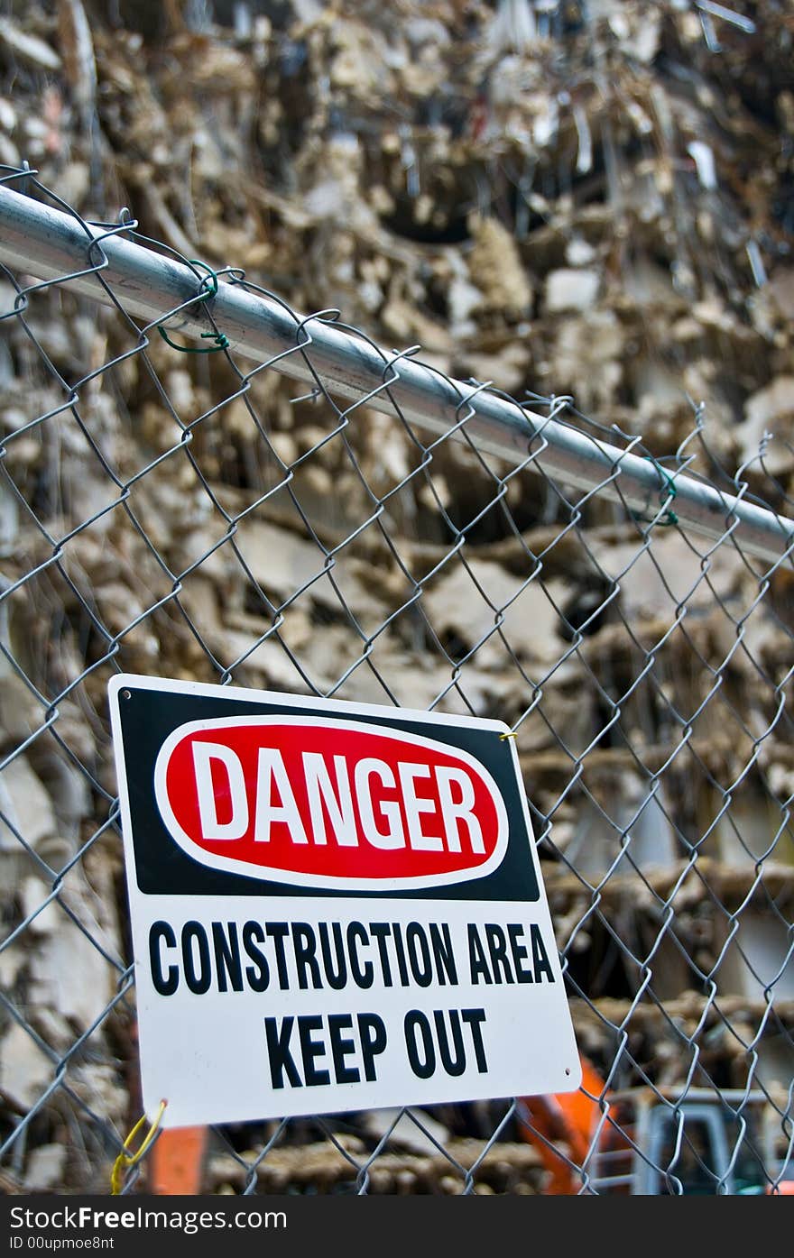 Warning sign posted on fence around massive demolition project, shallow depth of field - part of series. Warning sign posted on fence around massive demolition project, shallow depth of field - part of series