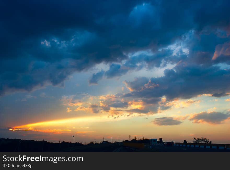 Colorful sunset with clouds and sunbeams over rural skyline. Colorful sunset with clouds and sunbeams over rural skyline