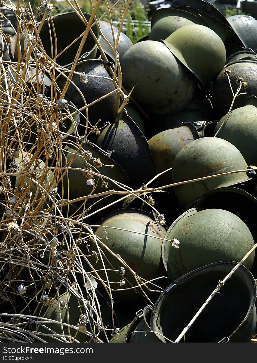 Abandoned Army helmets stacked up in the weeds. Abandoned Army helmets stacked up in the weeds