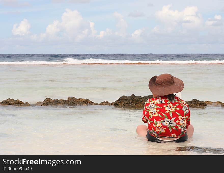 Woman reading in water, Fakarava, French Polynesia, facing the ocean. Woman reading in water, Fakarava, French Polynesia, facing the ocean