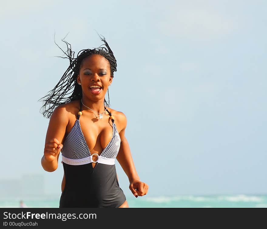 Attractive young black woman running on the beach.