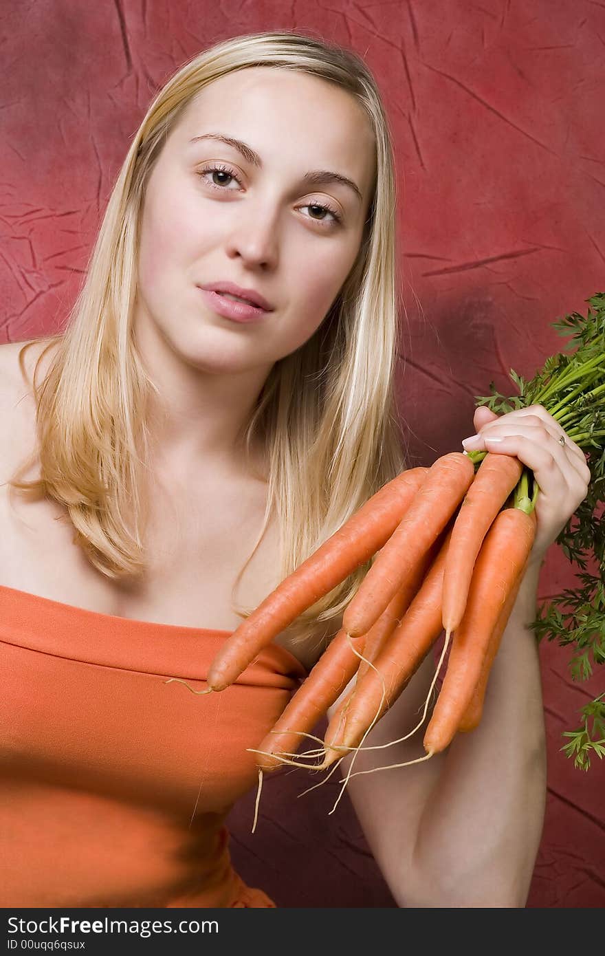 Young beautiful woman with the bunch of carrots. Young beautiful woman with the bunch of carrots