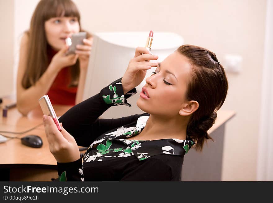 Young beautiful women applying make-up at office