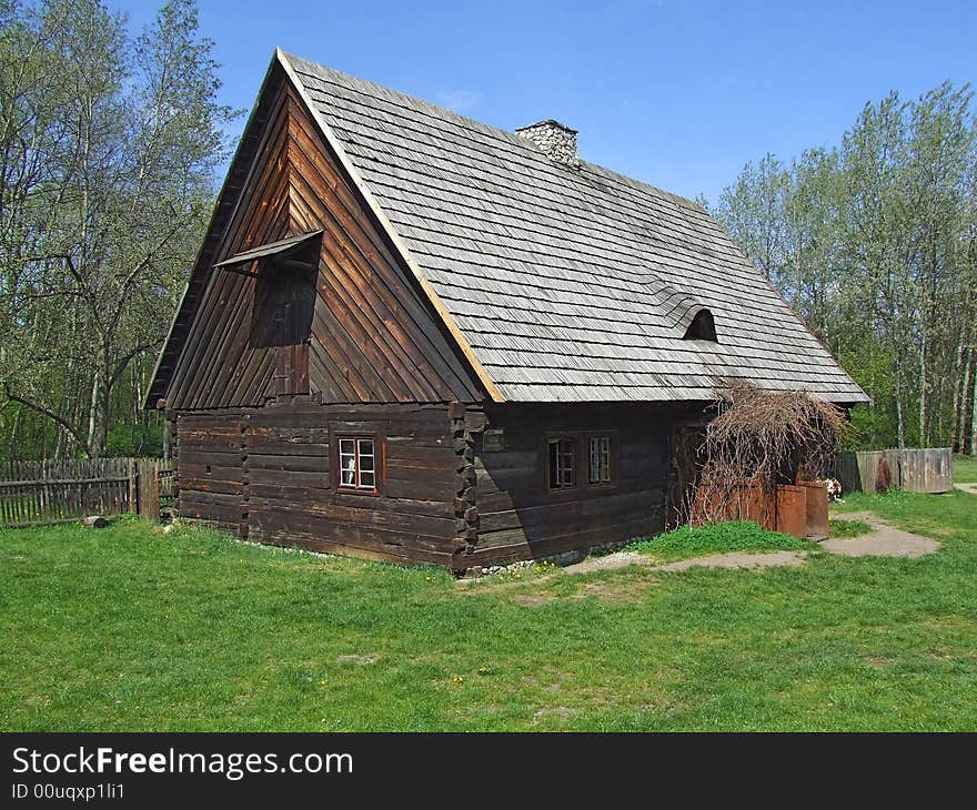 Old wooden hut in village, green grass around