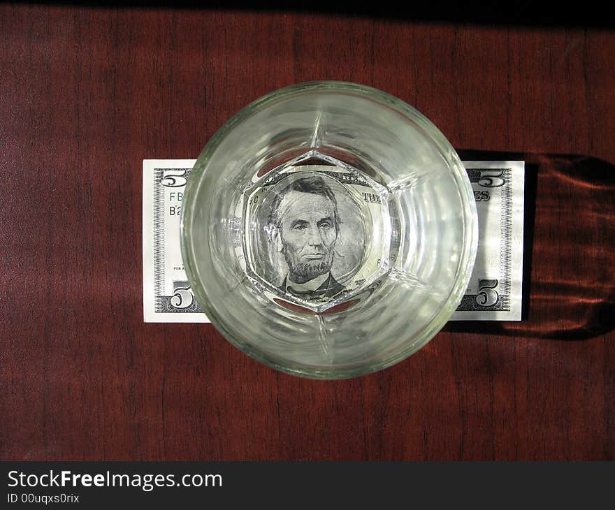 Banknote of $5 under transparent wisky glass. Banknote of $5 under transparent wisky glass