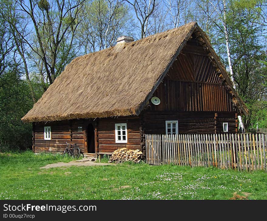 Old wooden hut in village, green grass around