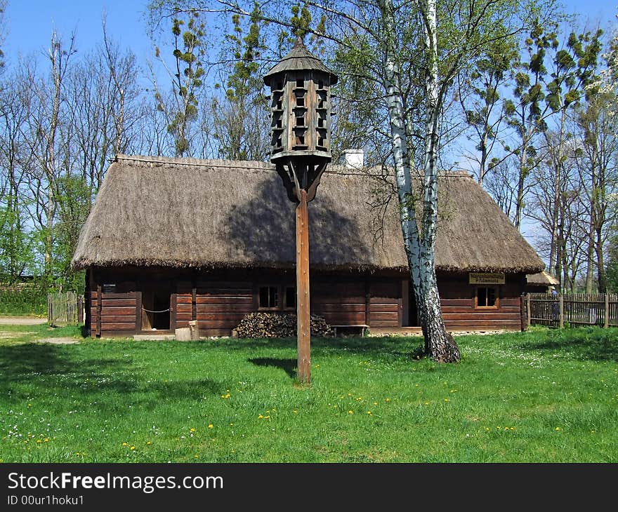 Old wooden hut in village, green grass around