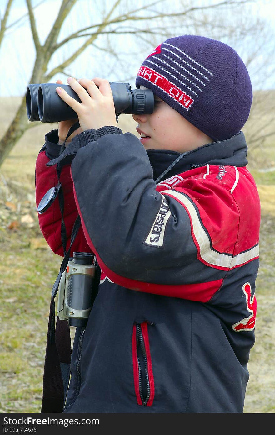 The boy of ten years observes into the binoculars nature or plays into the game with other children. The boy of ten years observes into the binoculars nature or plays into the game with other children