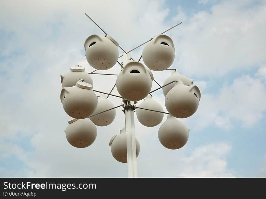 White birdhouses against a blue sky background with white clouds. White birdhouses against a blue sky background with white clouds