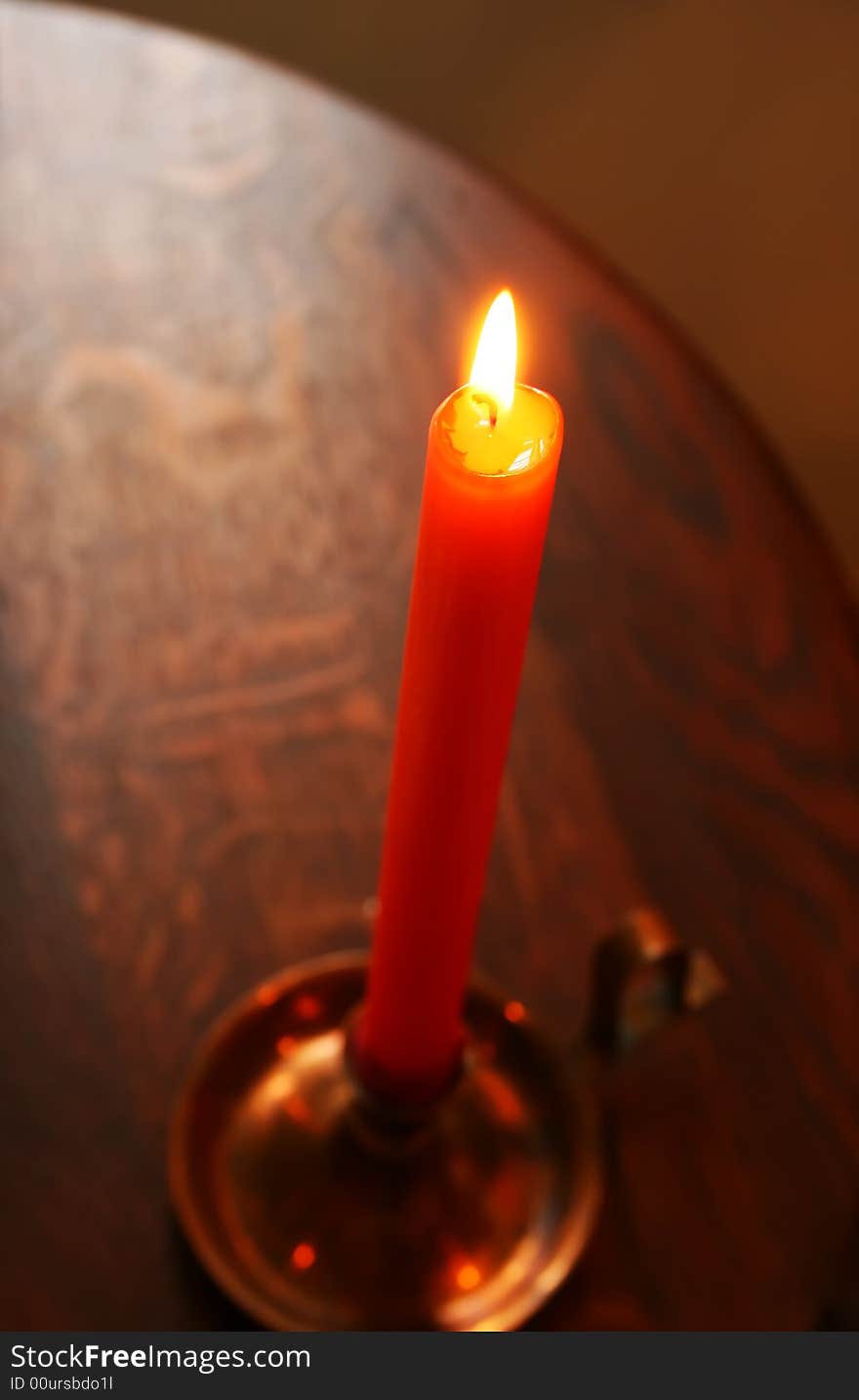 Burning of the Candle in a candlestick costing on a table. Burning of the Candle in a candlestick costing on a table.