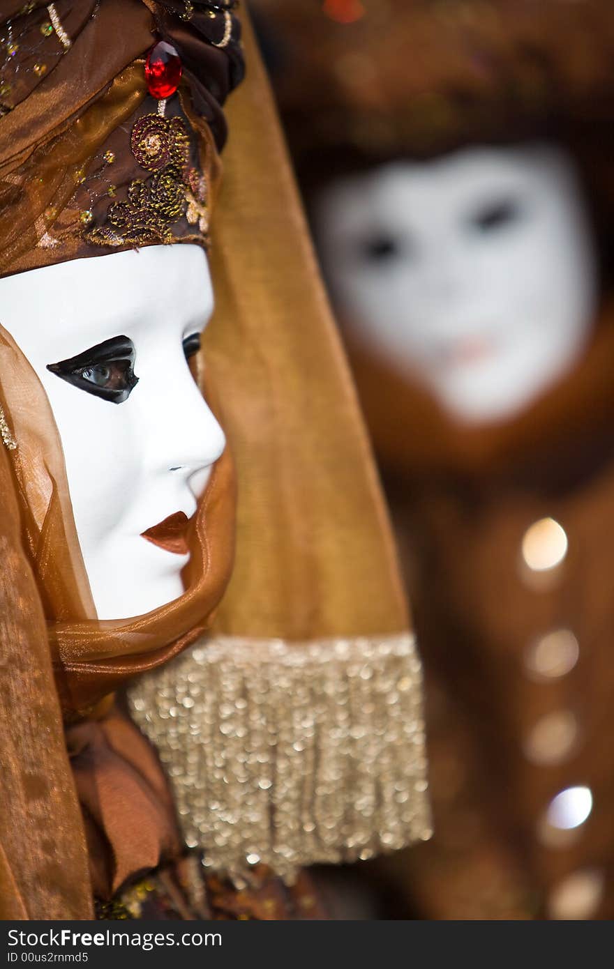 White mask with a brown costume at the Venice Carnival. White mask with a brown costume at the Venice Carnival