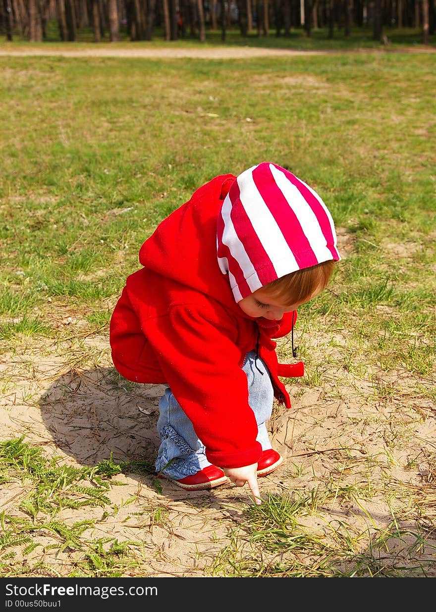 Little girl in a wood looks at a grass