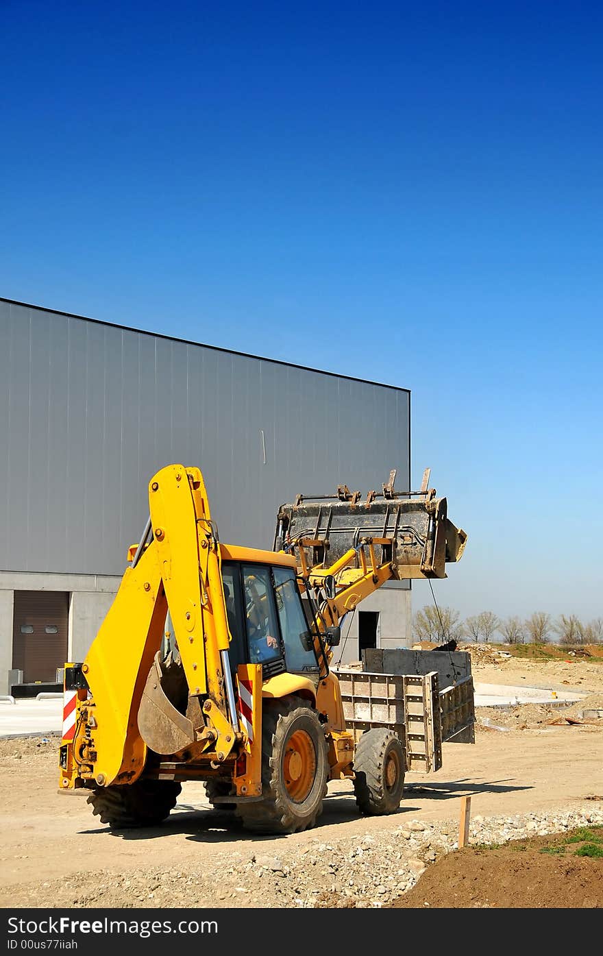 Yellow backhoe loader on construction site- side view