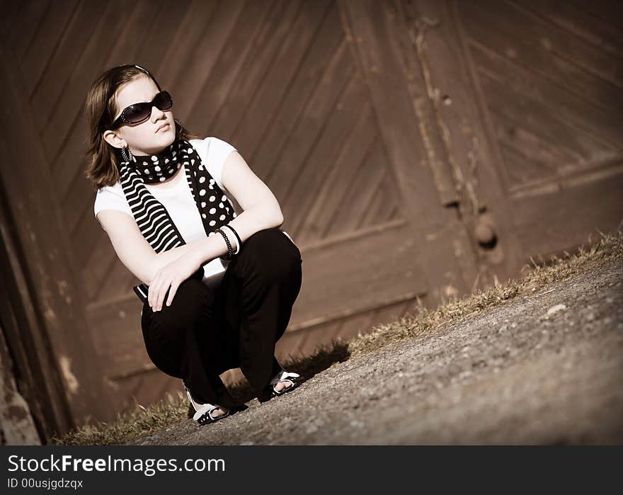 Portrait of a squatting tween girl in front of old double doors.  In sepia tone. Portrait of a squatting tween girl in front of old double doors.  In sepia tone.