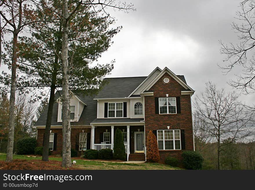 Large expensive brick home with dormer window and a landscaped yard.