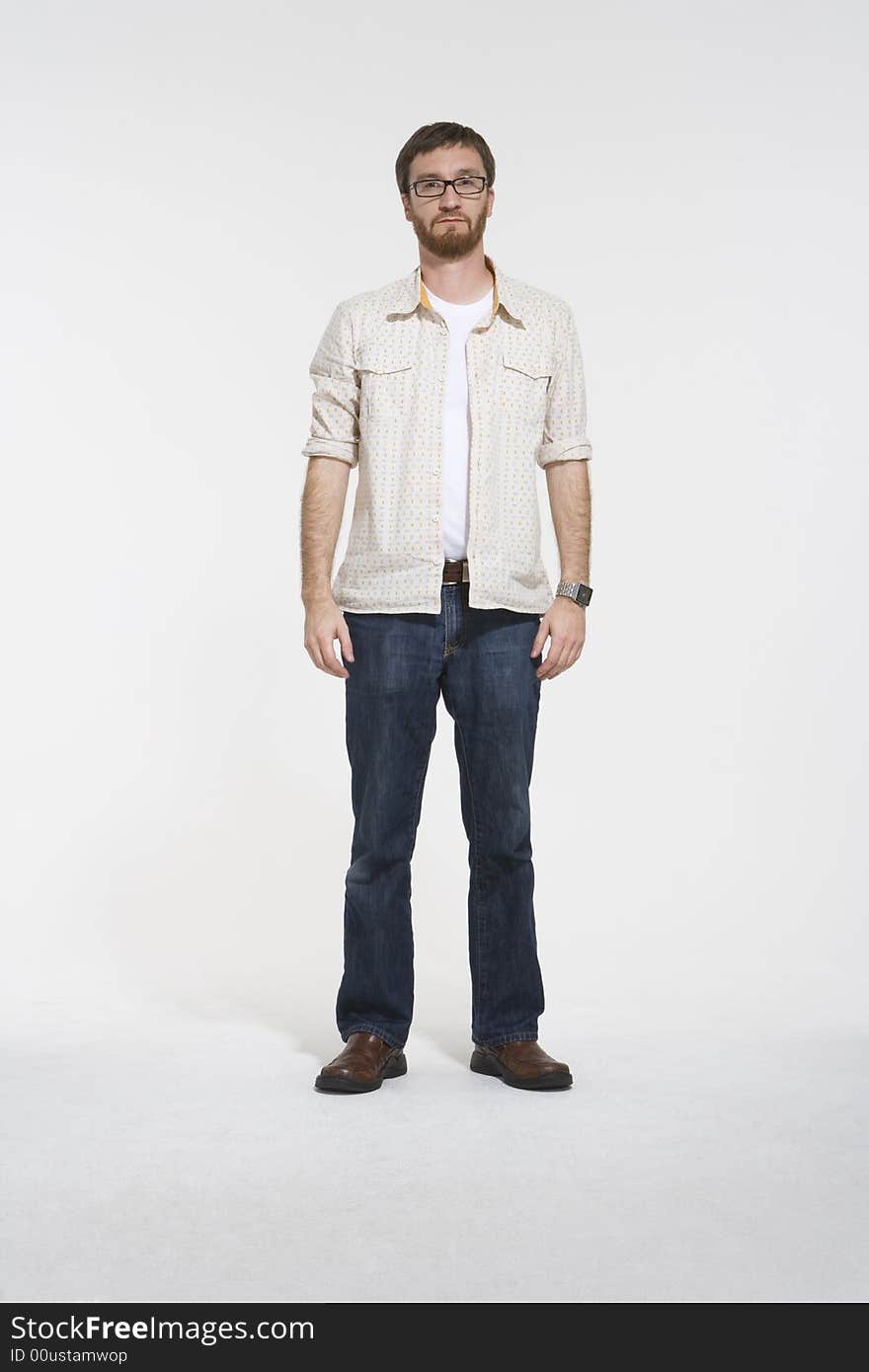 Full length photo of man a with beard standing inside a photostudio. Hewearing a creame pattern shirt and denim jeans. Full length photo of man a with beard standing inside a photostudio. Hewearing a creame pattern shirt and denim jeans.