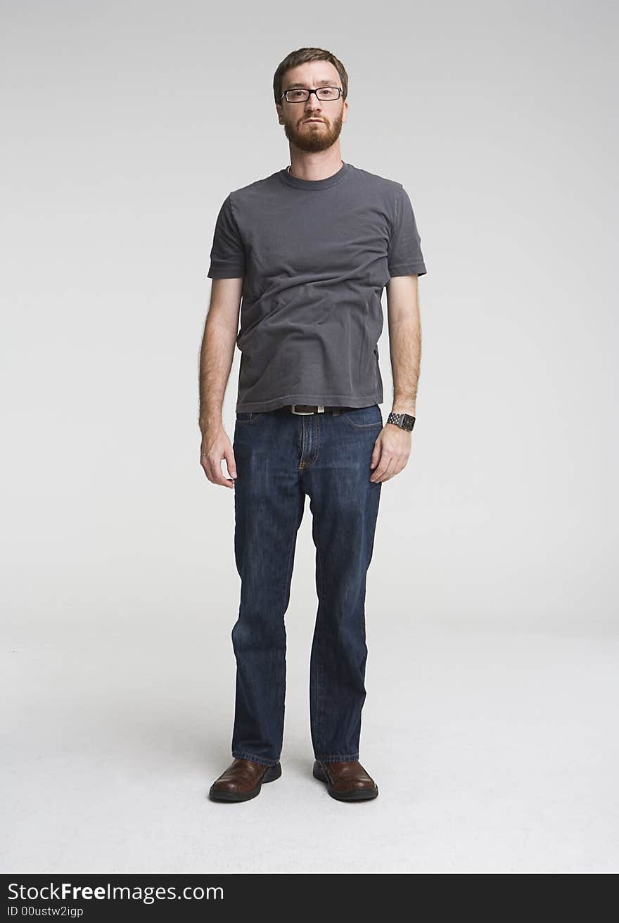 Full length photo of man a with beard standing inside a photostudio. His shirt is entirely wrinkled and he has serious expression on his face. Full length photo of man a with beard standing inside a photostudio. His shirt is entirely wrinkled and he has serious expression on his face.