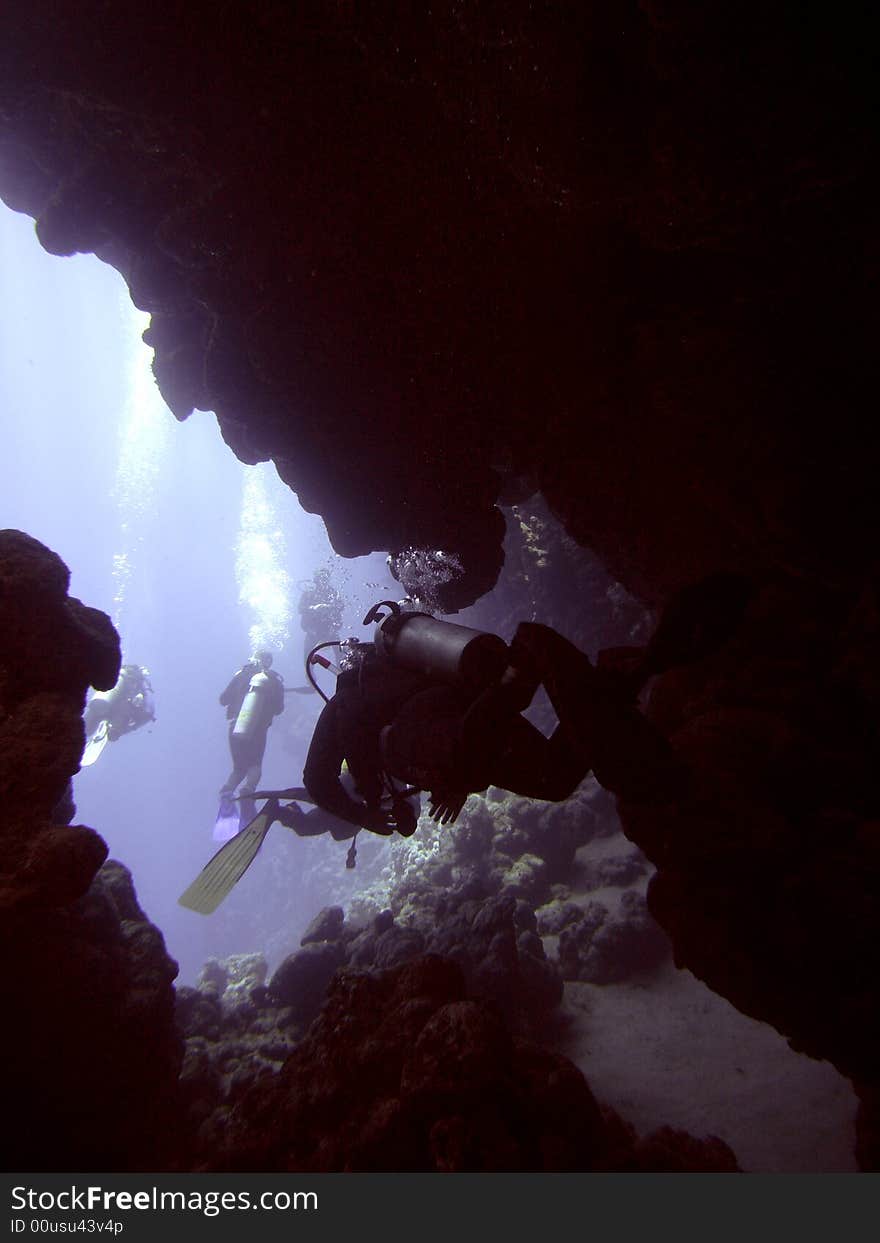 Dark cavern with divers swimming out