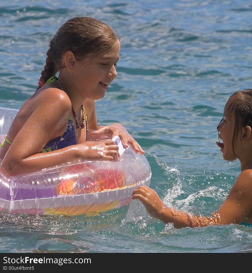 Two girls of teenager bath in a sea on a rubber circle. Two girls of teenager bath in a sea on a rubber circle